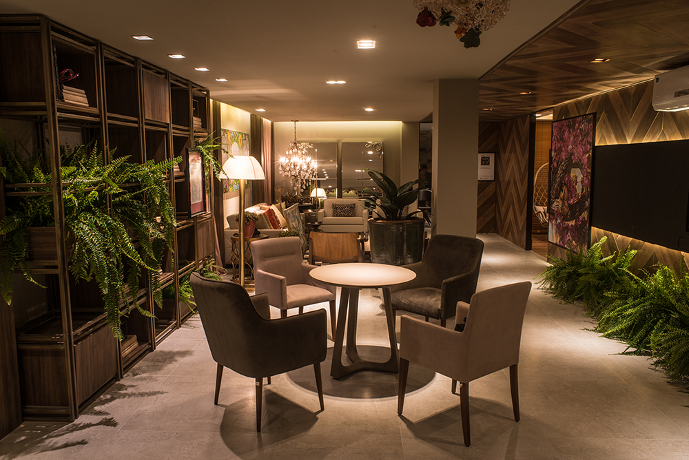 Lounge Primavera Rosa - Ana Paula Bastos, Edgard Ribeiro, Juliana Vilela, Veruska Matos e Vanessa Koehler. O nome do ambiente de 67m² remete ao mês tradicionalmente dedicado ao combate e prevenção do câncer feminino, chamado Outubro Rosa. A mensagem é transmitida na delicadeza dos painéis florais que vestem as paredes e nas plantas que brotam em vários pontos, em um clima primaveril. Para equilibrar o conjunto, tons de cinza nos estofados, revestimentos de parede na cor chumbo e algumas peças amadeiradas.