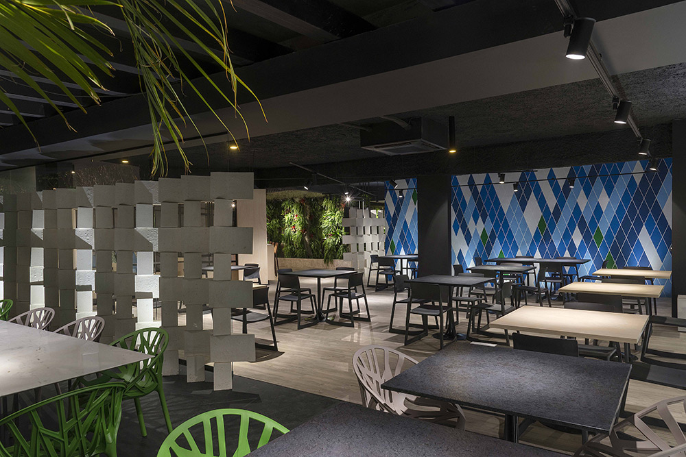 Restaurante - Studio HuB. Os elementos modernistas da cidade são reverenciados no ambiente de 190m², a começar pela linha de móveis e as artes dos murais, ambas assinadas pelo Studio HuB. Lounge, varanda, bar e salão de refeições se conectam visualmente pelo uso de materiais em comum, como concreto, piso vinílico e painéis em MDF.