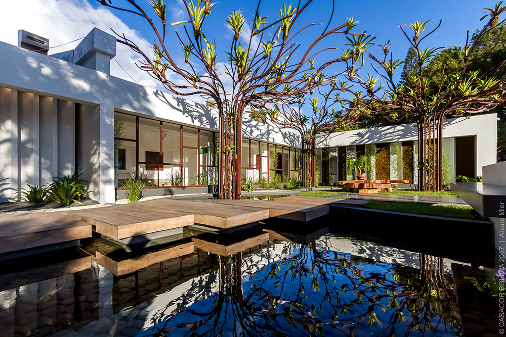 TEA GARDEN - CARLA BLANCO, JOSELYNE ADAD E LUIS EDUARDO AÑEZ. Os princípios de Kazuo Shinohara e o Jardim Botânico de Cingapura orientam o projeto, com suas três estruturas metálicas chamadas “Árvores de Bromélias”. O lago é percorrido sobre placas em madeira, ressaltando o contato com a natureza para favorecer o relaxamento e a meditação.