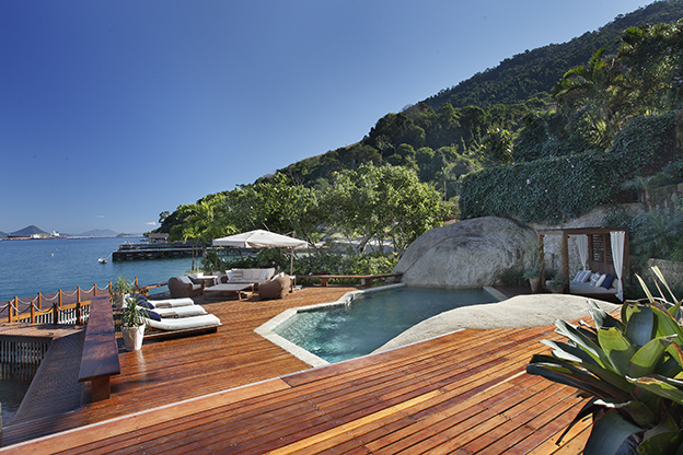 Paola Ribeiro - Casa em Angra dos Reis. Na encosta do morro, de frente para o mar, a piscina de formato abstrato se assemelha a um lago natural.