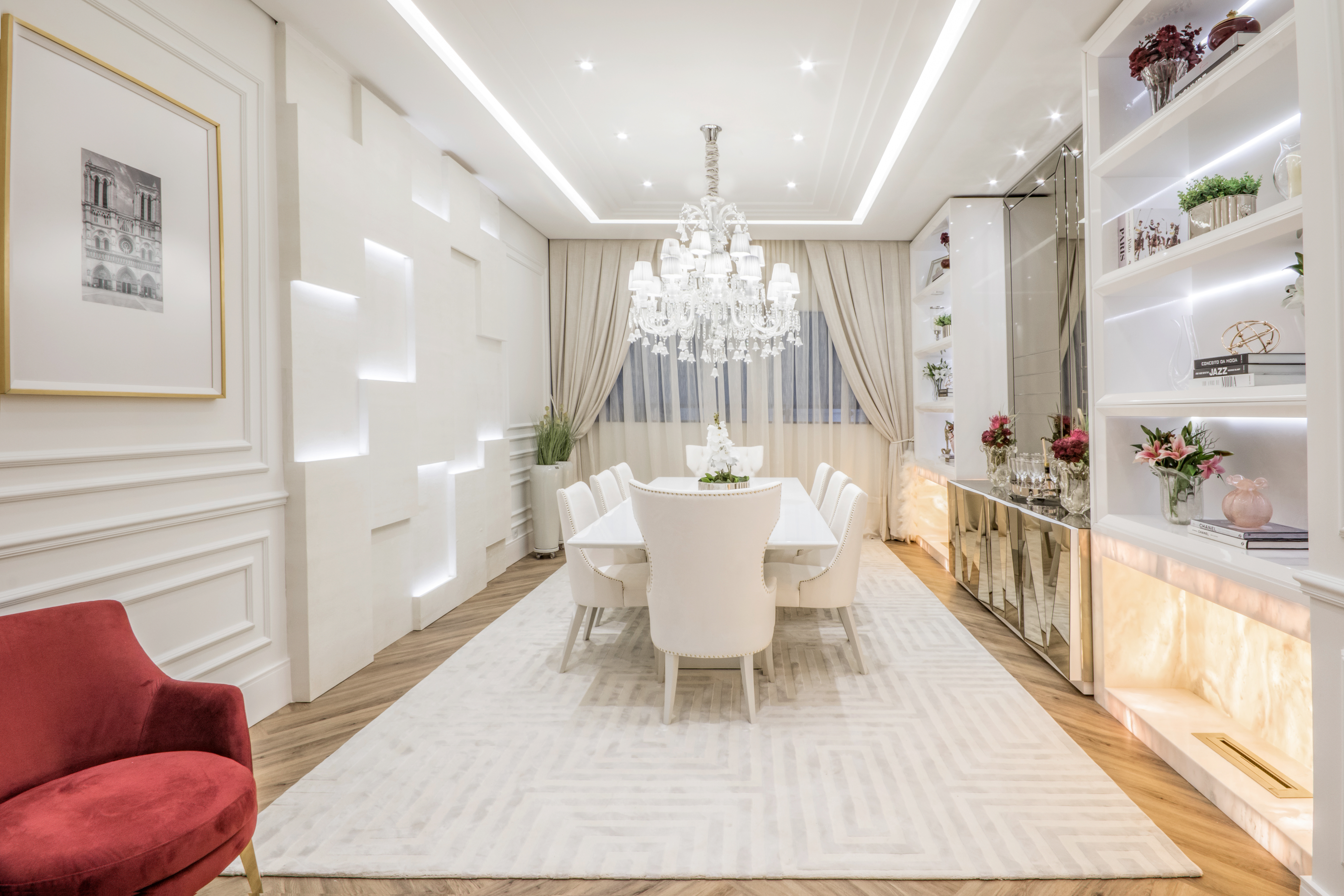 Sala de Jantar - Kátia Herzog. O estilo clássico parisiense ganha uma leitura contemporânea nestes 32 m². O off white foi o principal tom escolhido, enquanto o piso de madeira traz calor ao ambiente. Vários móveis foram desenhados pela profissional, como o buffet. As cadeiras foram revestidas em couro reciclado e tecido ecológico, antimanchas e repelente a líquidos. A pedra translúcida ressalta a simetria da estante - outra característica do clássico.