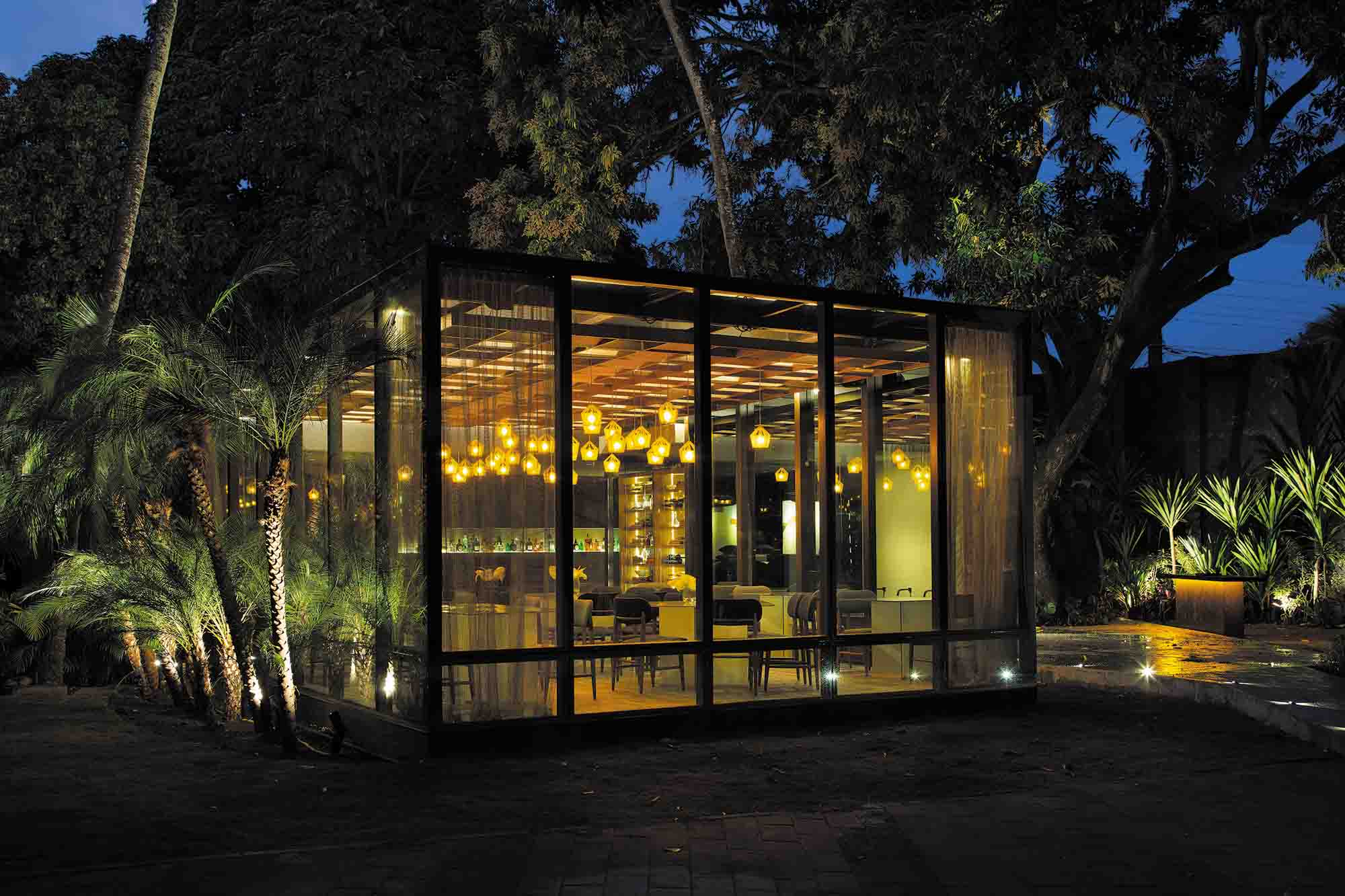 Restaurante Vivix - Dubeux Vasconcelos Arquitetura. O restaurante foi inspirado nos contornos de um cubo mágico e envelopado por vidro, que ora reflete o verde do entorno, ora explode luz. O terraço e o espelho d’água integram os ambientes interno e externo em total harmonia com o paisagismo. A contemporaneidade do projeto se revela na construção sustentável, com uso de materiais naturais. O mobiliário e a iluminação foram assinados pelos arquitetos.