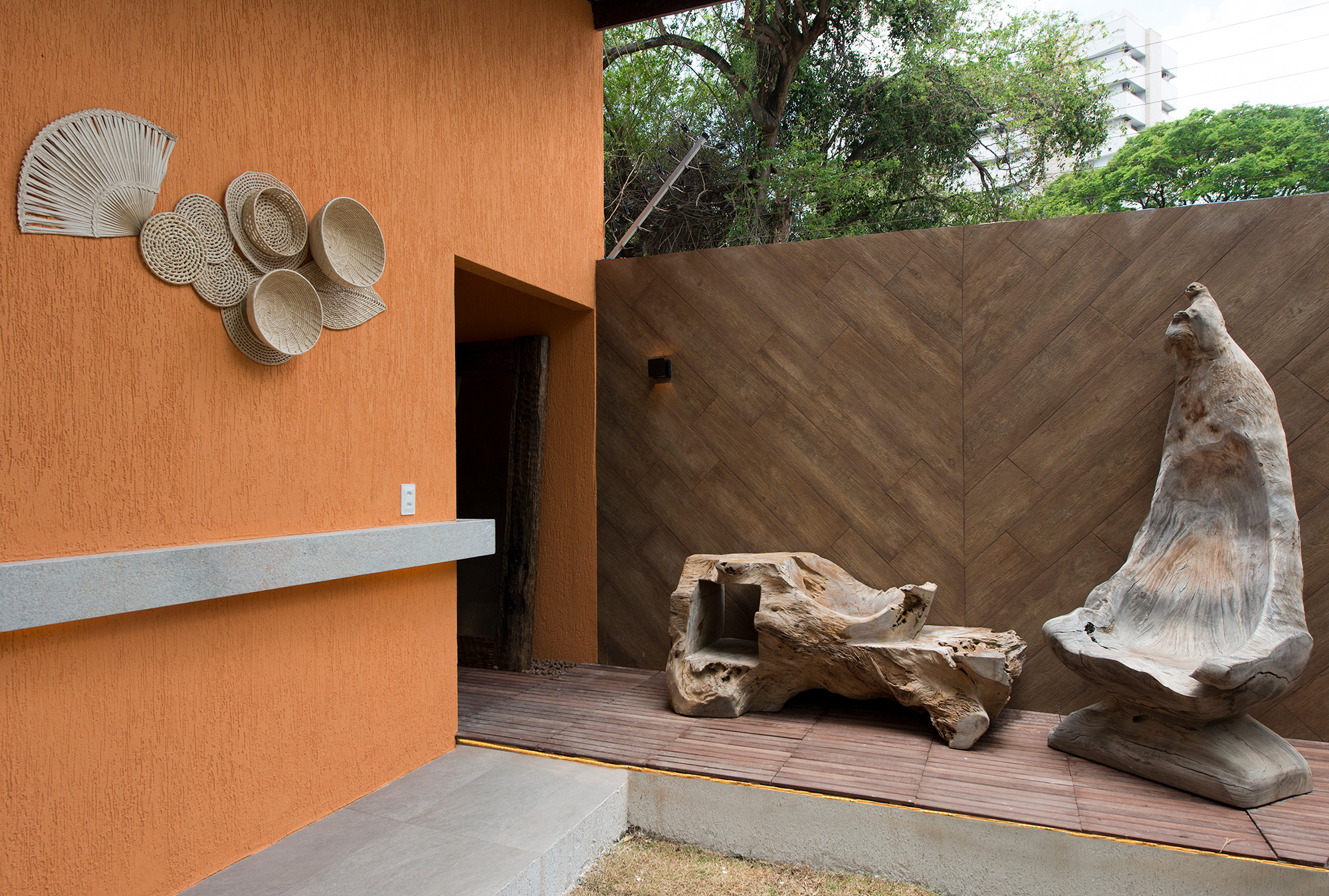 Pedro Athayde - BPK. O ar do sertão é traduzido por meio de materiais naturais e acabamentos rústicos, a começar pelo piso. Similar ao concreto natural e batido, suas cores vivas lembram o calor do interior. Um tablado de madeira maciça une os espaços interno e externo e proporciona conforto térmico. O acabamento com porcelanato confere um toque moderno, auxiliando também na acústica dos banheiros e garantindo a privacidade e a usabilidade do ambiente.