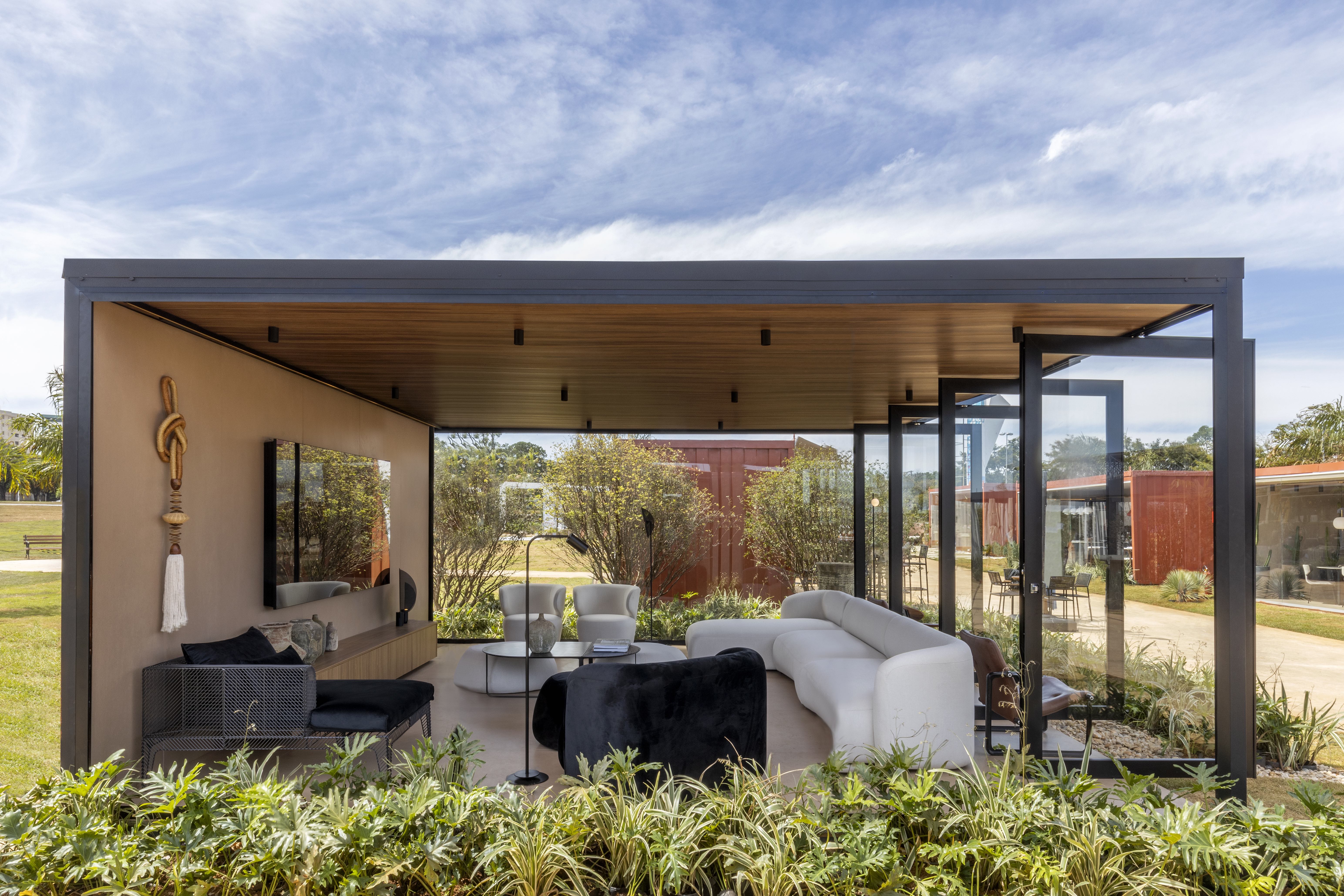 Danilo Noleto- Casa Bubble. Abraçado por um lindo jardim,  o ambiente projetado pelo arquiteto Danilo Noleto foi pensado para ser um espaço de refúgio. A poltrona Bubble é o ponto de partida da inspiração. Este local de estar e se sentir bem tem predominância de madeira com um toque minimalista de simplicidade. Os tons terrosos, pastéis e secos e as esquadrias pretas em contraponto com tons claros deixam o ambiente sóbrio e aconchegante. O mobiliário orgânico valoriza o design e os poucos elementos de iluminação deixam a atmosfera segura e convidativa. 