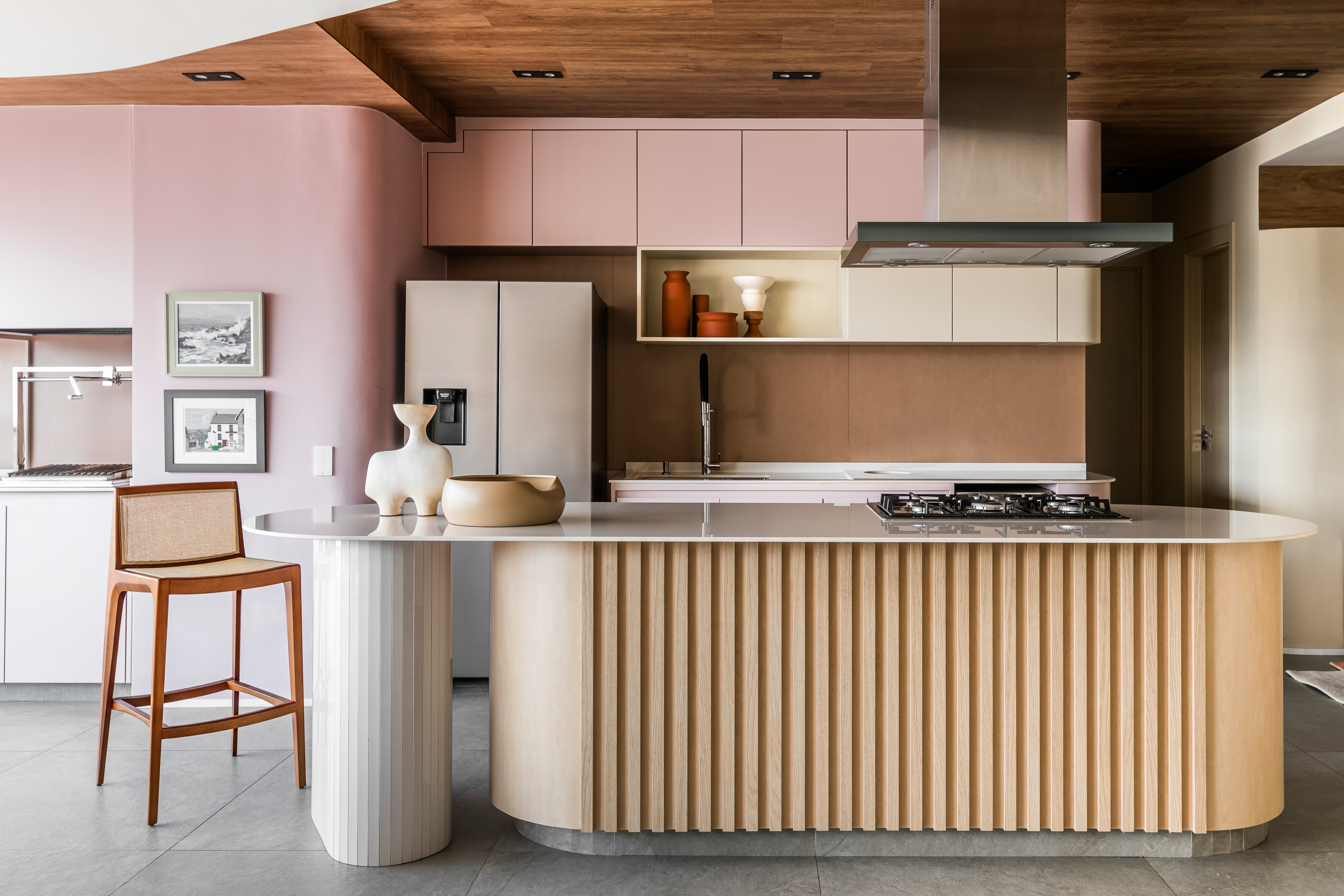 Cozinha rosa, plantas e curvas marcam apê assinado por Ricardo Abreu. Na foto, cozinha integrada à sala de TV, Marcenaria rosa e bancada,